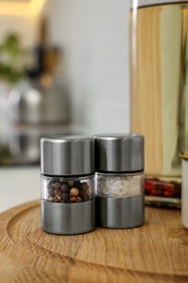 Salt and pepper mills on wooden board in kitchen. Space for text