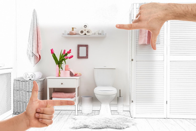 Image of Man showing frame gesture and making bathroom real out of drawing
