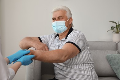 Doctor taking care of senior man with protective mask at nursing home