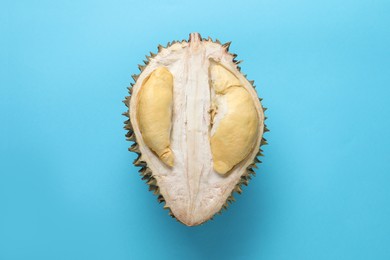 Photo of Half of fresh ripe durian on light blue background, top view