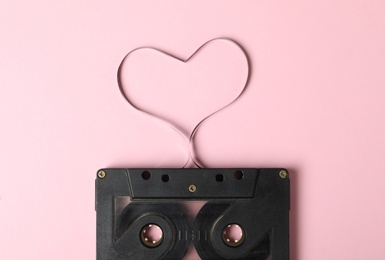 Music cassette and heart made with tape on pink background, top view. Listening love song