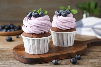 Sweet cupcakes with fresh blueberries on wooden table