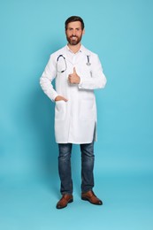Full length portrait of doctor with stethoscope on light blue background