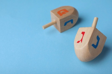 Hanukkah traditional dreidels with letters Gimel, Nun and Pe on light blue background, space for text