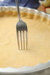 Photo of Making holes in raw dough for traditional English apple pie with fork, closeup