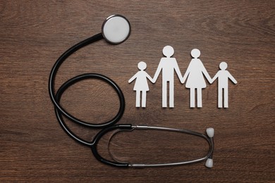 Photo of Paper family cutout and stethoscope on wooden background, flat lay. Insurance concept