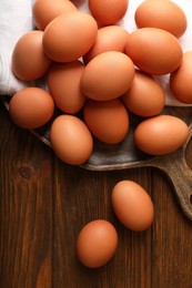 Photo of Raw brown chicken eggs on wooden table, flat lay
