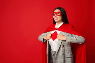 Confident businesswoman wearing superhero costume under suit on red background, space for text