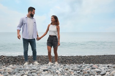 Happy young couple on beach near sea. Space for text
