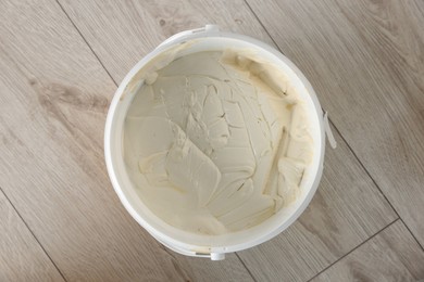 Bucket with plaster and putty knife on floor indoors, top view