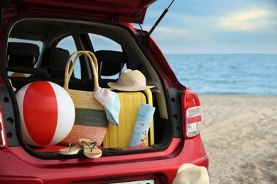 Red car with luggage on beach, closeup. Summer vacation trip