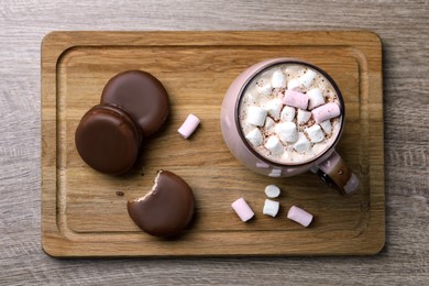 Tasty choco pies and cocoa with marshmallows on wooden table, top view