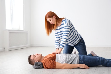 Woman practicing first aid on unconscious man indoors