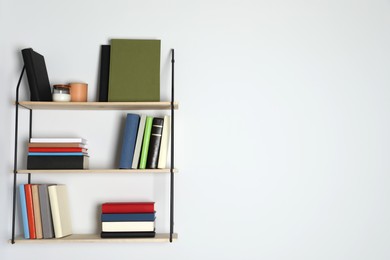 Photo of Shelves with many hardcover books on white wall. Space for text