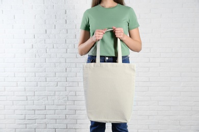 Woman with eco bag near brick wall. Mock up for design
