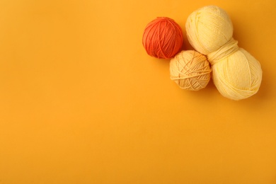 Soft colorful woolen yarns on yellow background, flat lay. Space for text