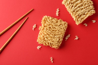 Flat lay composition with quick cooking noodles and chopsticks on color background