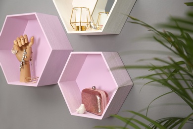 Hexagon shaped shelves with different stuff on grey wall. Interior design