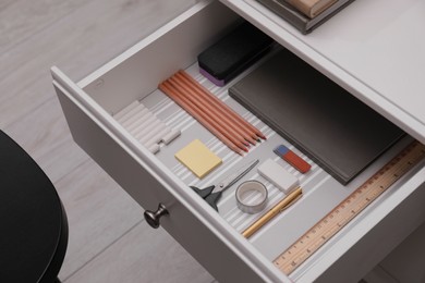 Photo of Office supplies in open desk drawer indoors. above view