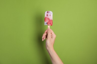 Woman holding berry popsicle on green background, closeup