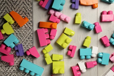 Colorful plastic building blocks on floor, flat lay