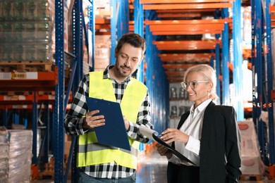 Manager and worker in warehouse with lots of products