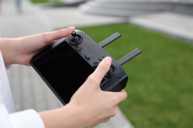 Woman with modern drone controller outdoors, closeup