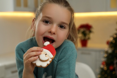 Cute little girl with Christmas gingerbread cookie at home