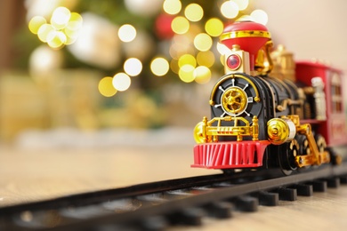 Photo of Toy train and railway on floor against Christmas lights. Space for text