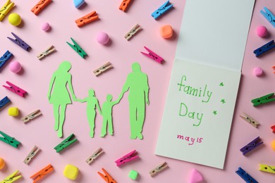 Happy International Family Day. Flat lay composition with notebook and paper people cutout on pink background