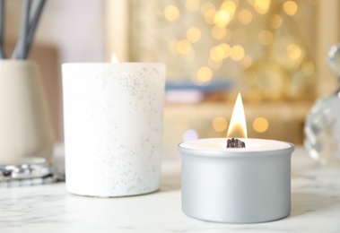 Burning candles in holders on white table