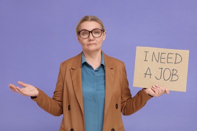 Photo of Unemployed senior woman holding cardboard sign with phrase I Need A Job on purple background