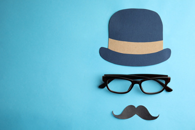 Photo of Eyeglasses, paper mustache and hat on light blue background, flat lay with space for text. Happy father's day
