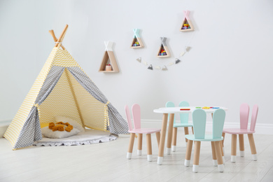 Photo of Cute children's room interior with teepee tent and little table