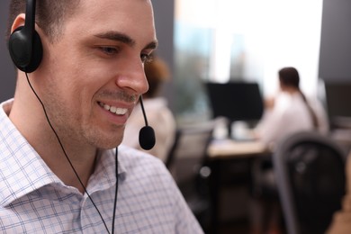 Young call center operator with headset working in modern office, closeup