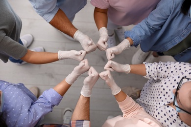 Group of people in white medical gloves showing thumbs up indoors, top view