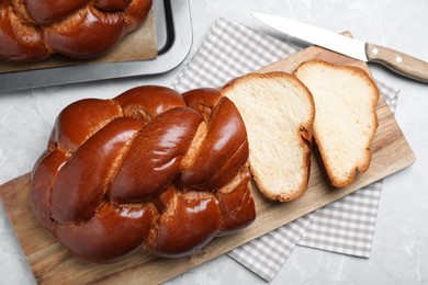 Photo of Cut homemade braided bread on grey table, flat lay. Traditional Shabbat challah