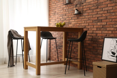 Photo of Elegant room interior with wooden table near brick wall