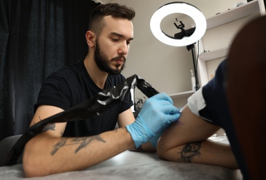 Photo of Professional tattoo master working with client in salon