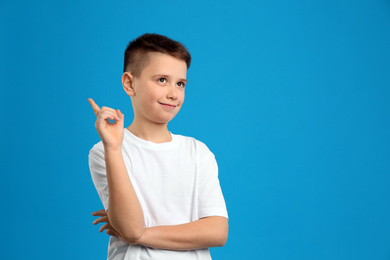 Portrait of preteen boy on light blue background, space for text