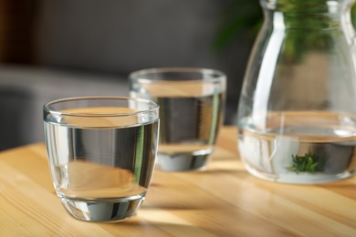 Glass of water on wooden table indoors, space for text. Refreshing drink