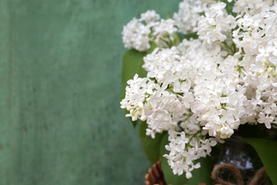 Photo of Beautiful lilac flowers near green wall, closeup. Space for text