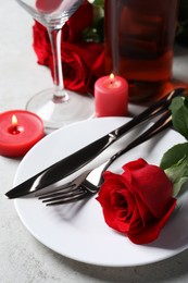 Photo of Beautiful place setting with dishware, candles and rose for romantic dinner on light table, closeup
