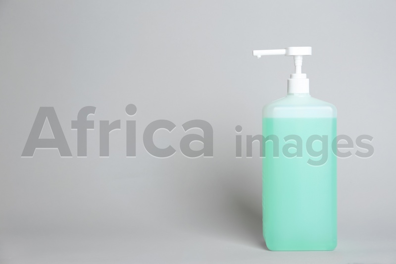 Dispenser bottle with antiseptic gel on light grey background. Space for text