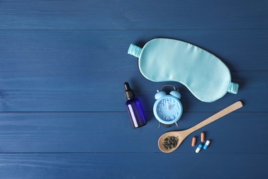 Alarm clock, sleeping mask and different remedies for insomnia treatment on blue wooden table, flat lay