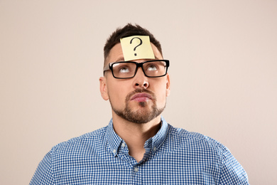Man in eyeglasses with question mark on grey background