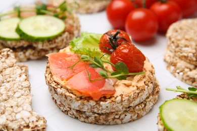Crunchy buckwheat cakes with salmon, tomatoes and greens on white table, closeup
