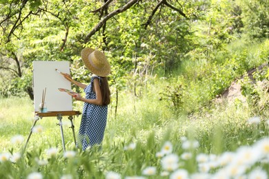 Little girl painting on easel in picturesque countryside