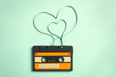 Music cassette and hearts made with tape on turquoise background, top view. Listening love song