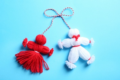 Photo of Traditional martisor shaped as man and woman on light blue background, top view. Beginning of spring celebration